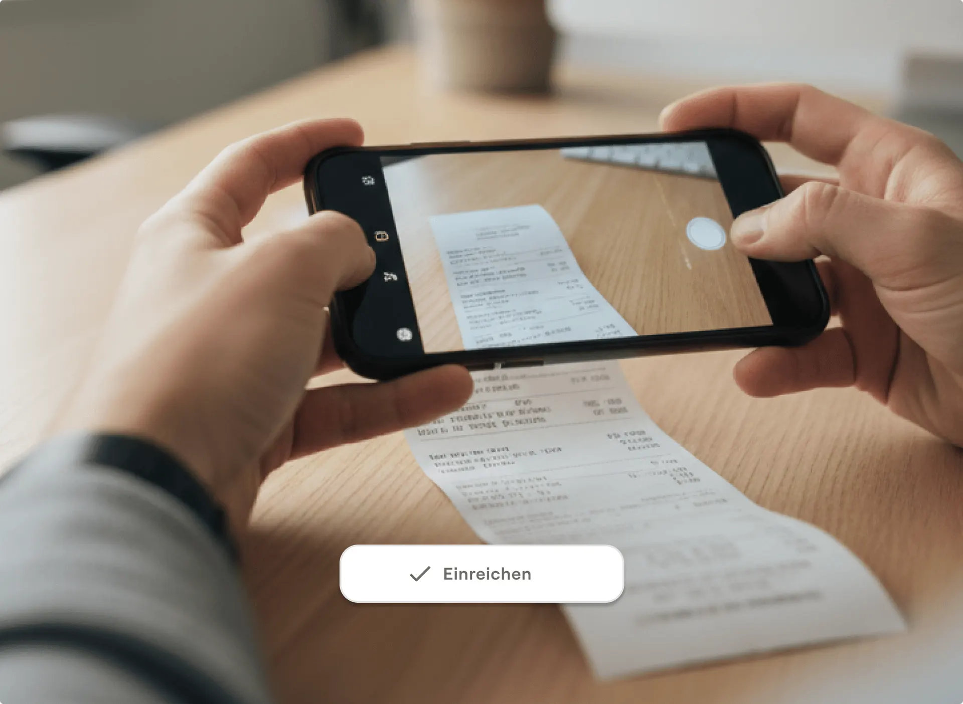 Zwei Hände fotografieren mit einem Smartphone einen Kassenbon auf einem Holztisch, darunter die Schaltfläche „Einreichen“