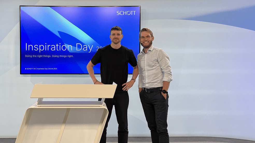 Zwei Maenner stehen neben einem Rednerpult vor einer Leinwand mit der Titelfolie „Inspiration Day 2025“