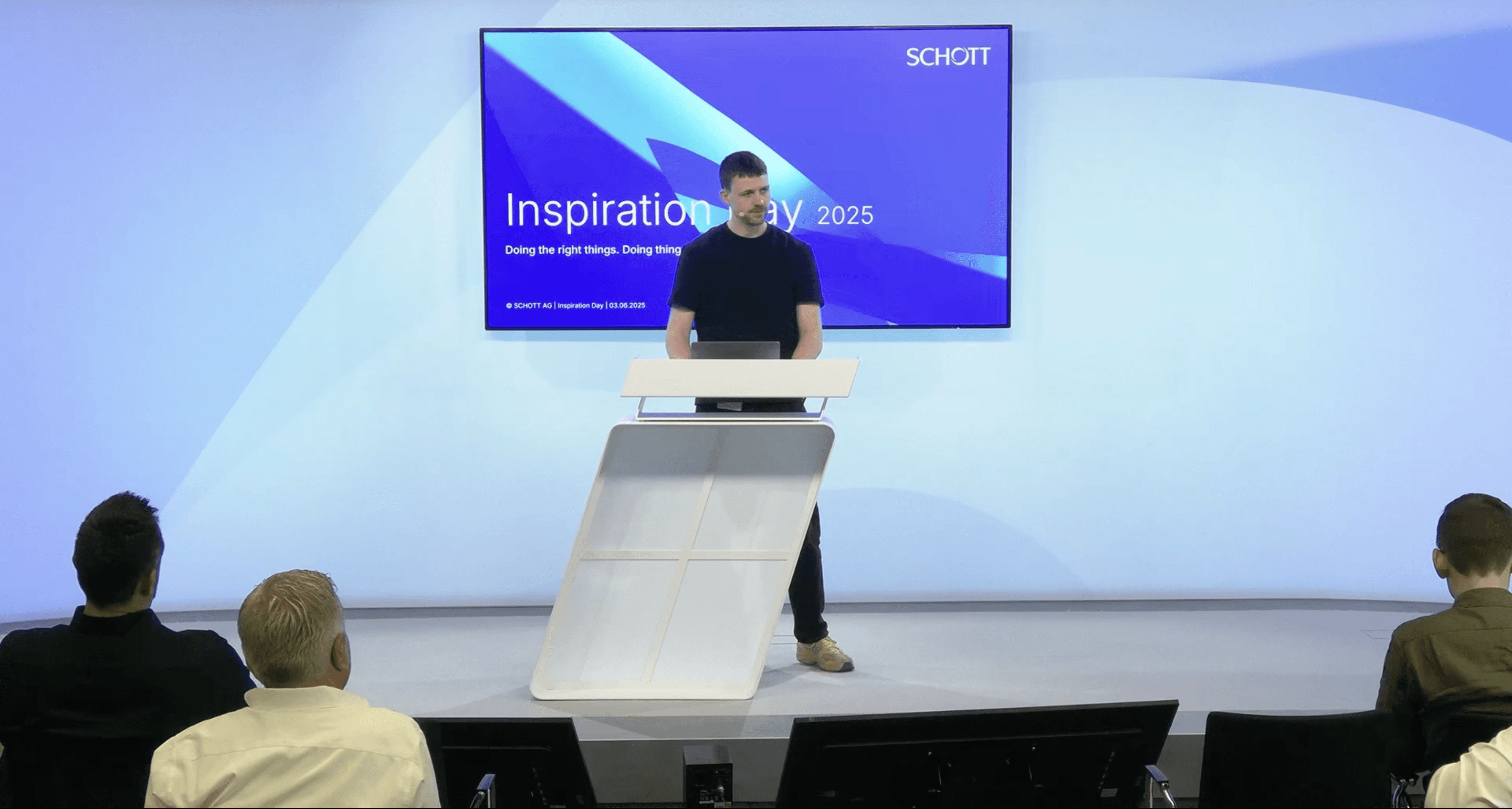 Ein Mann spricht an einem Rednerpult vor der Leinwand „Inspiration Day 2025“, im Vordergrund das sitzende Publikum