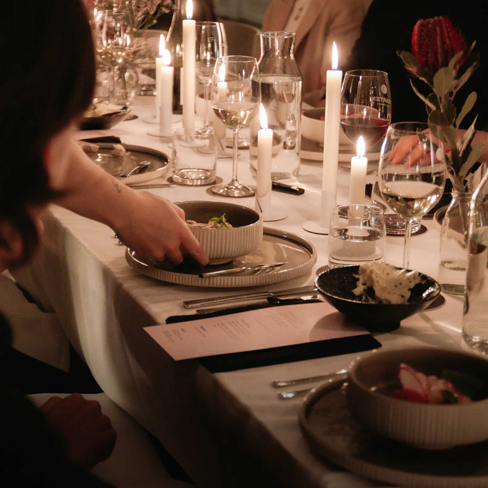 Detail photo of the executive dinner event with a set table, drinks and people in conversation.
