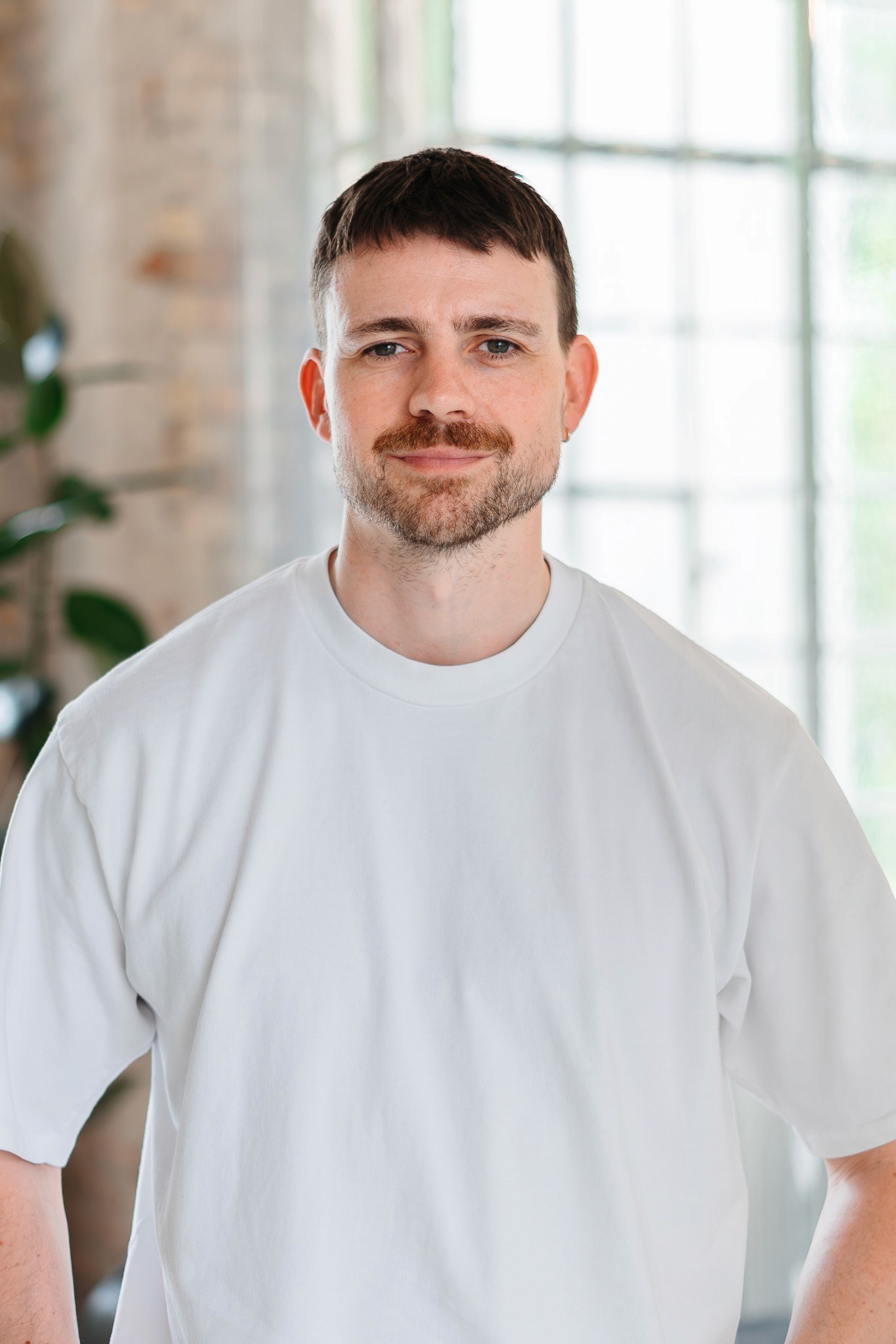 Portrait of Nico Wohlgemuth, managing director of DAYONE, against a bright background with large windows.