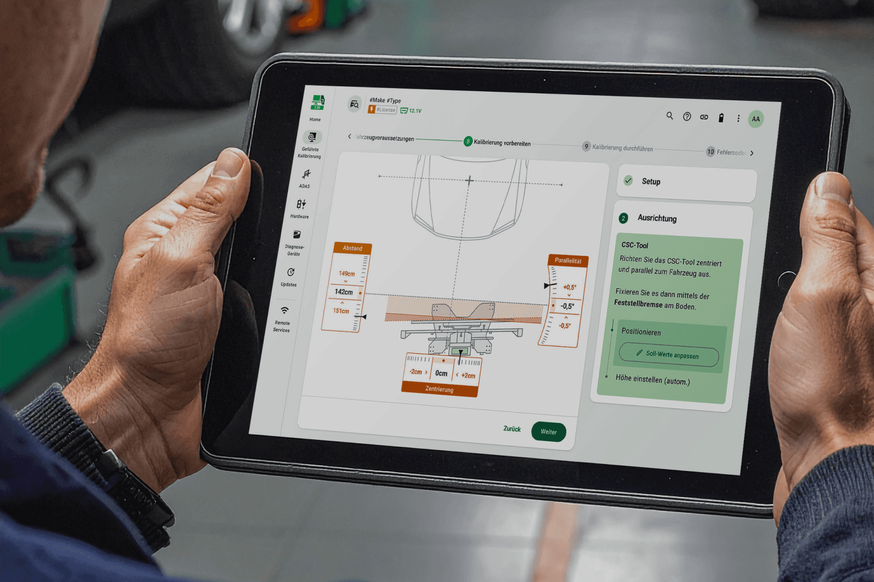 A workshop technician holding a tablet with the guided ADAS calibration: distance, parallelism and centring of the CSC tool.