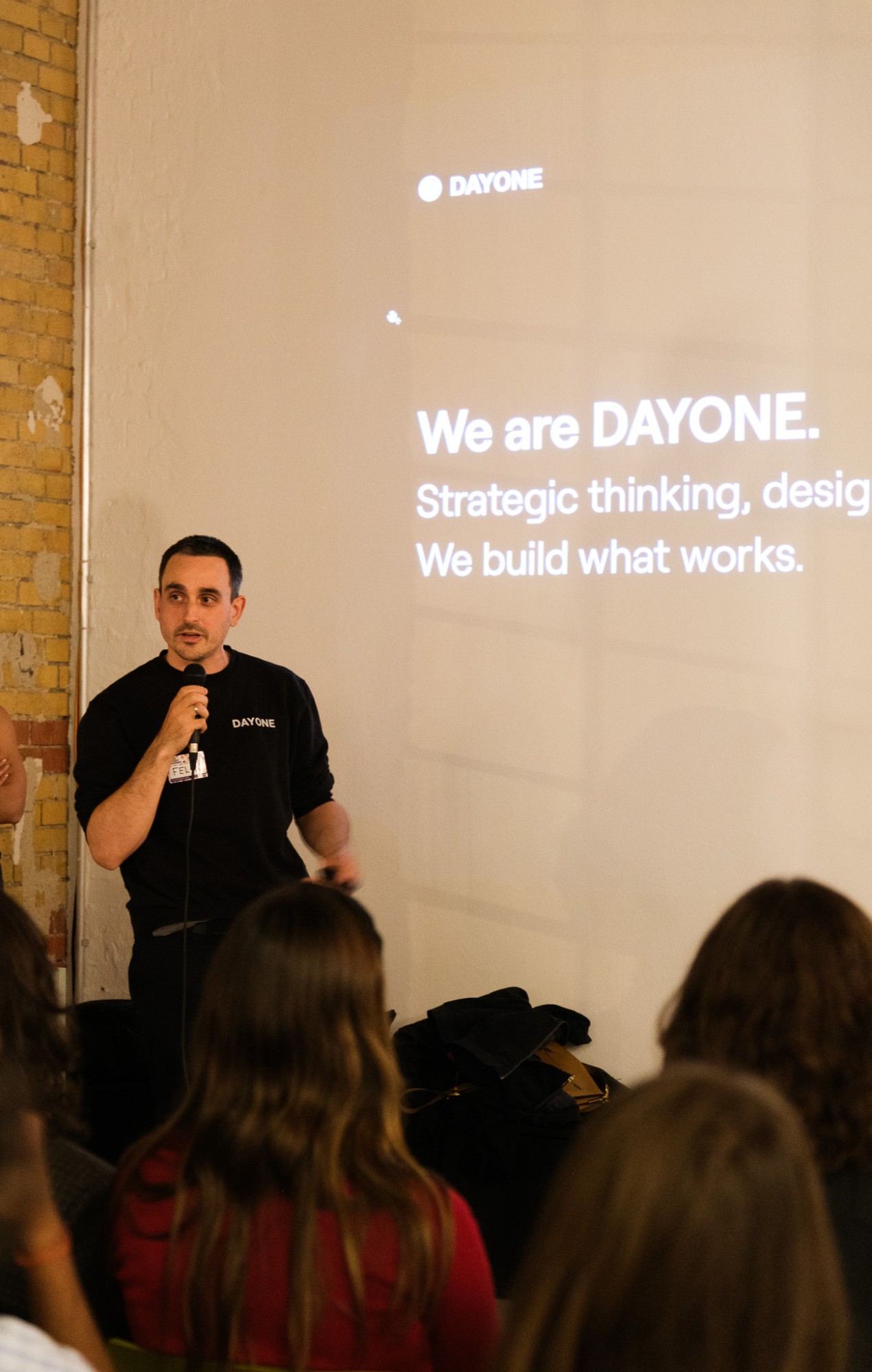 Felix Hoge von DAYONE begrüßt die Gäste, hinter ihm die Folie We are DAYONE. We build what works.